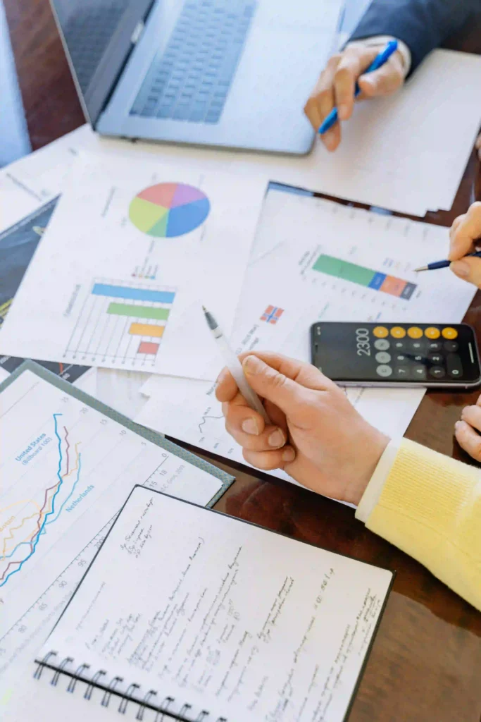 This image shows a business or financial planning scene of top digital marketing strategist in kerala Two people are working together with various documents and reports laid out on a table